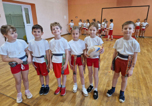 Dzieci stoją w rzędzi z piłka do ruggby