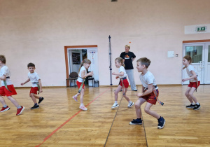 Dzieci z jajowata piłką biegają po sali gimnastycznej