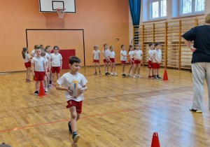 Chłopiec biegnie z piłka do pachołka