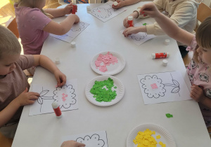 Dzieci przy stoliku wyklejają środek kwiatka