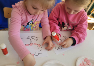 Dziewczynki wyklejają środek kwiatka na różowo