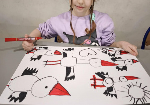 Dziewczynka maluje bocianom czerwone dzioby