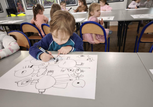 Chłopiec maluje na czarno kawałek skrzydła bociana