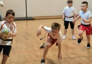 Chłopiec biegnie z piką do rugby