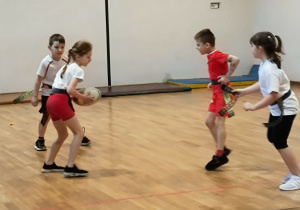 Dziewczynka trzyma w rękach piłkę do rugby