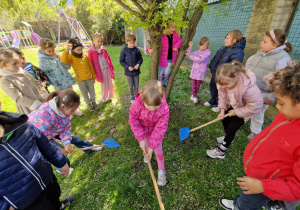 Dzieci grabią trawę pod drzewem