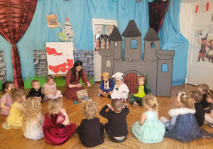 Dzieci siedzą w kole przy zamku