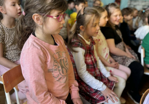 Dzieci siedza i oglądają przedstawienie