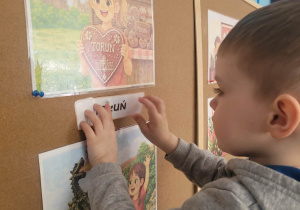 Chłopiec przyczepia napis Toruń