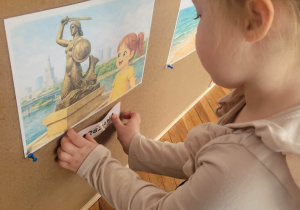 Dziewczynka przyczepia napis Warszawa