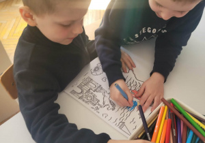 Chłopcy przy stole koloruja część dekoracji