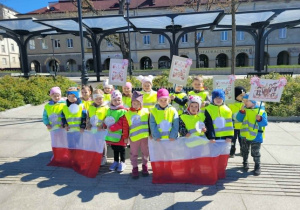 Dzieci stoją z flagami trzymanymi przed sobą