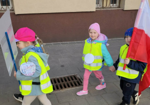 Dzieci idą z flagami i transparentsmi w pochodzie